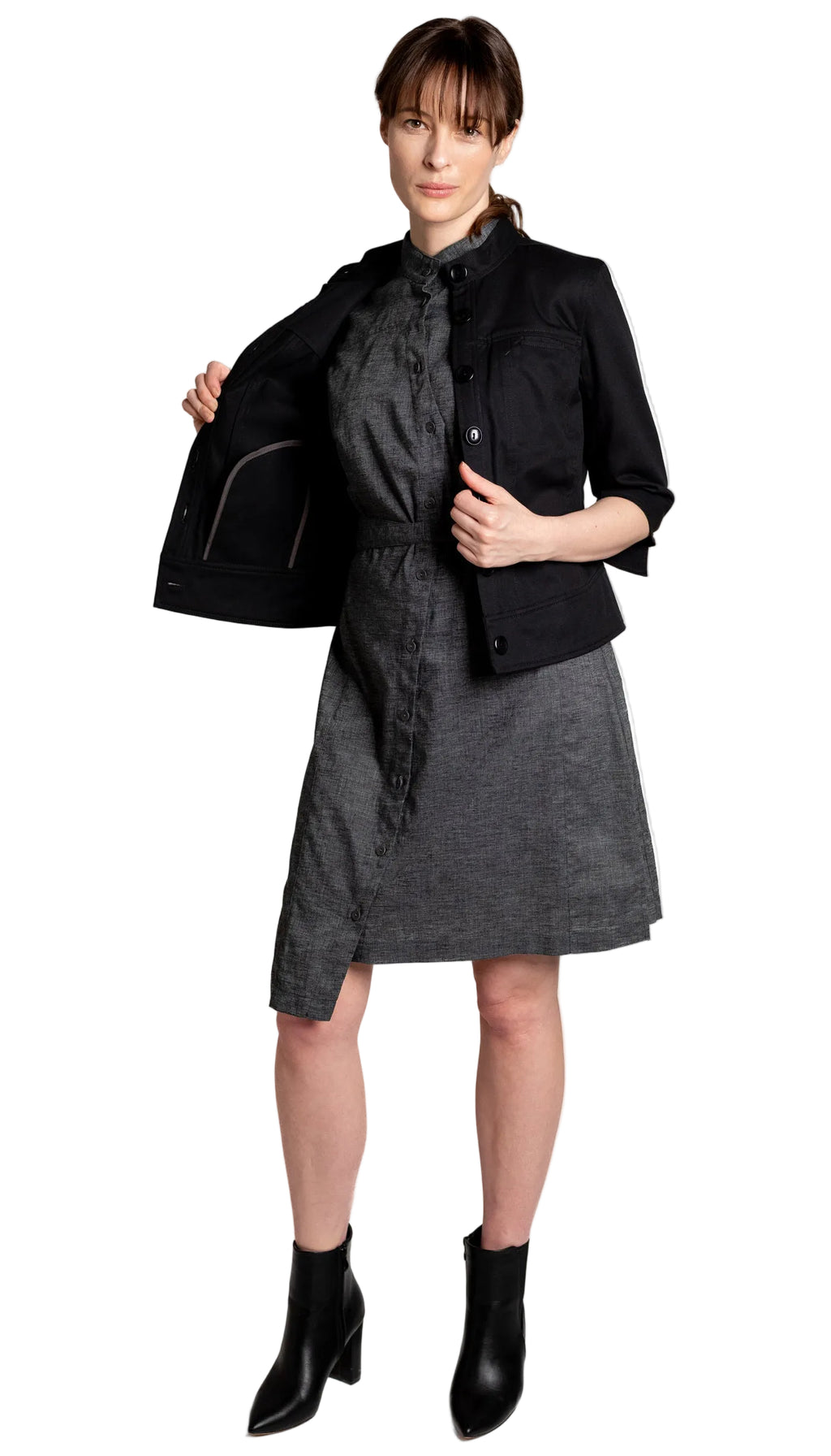 Woman wearing a black jacket over a gray dress on a white background